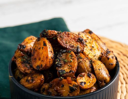 Bowl of roasted potatoes garnished with herbs and spices.