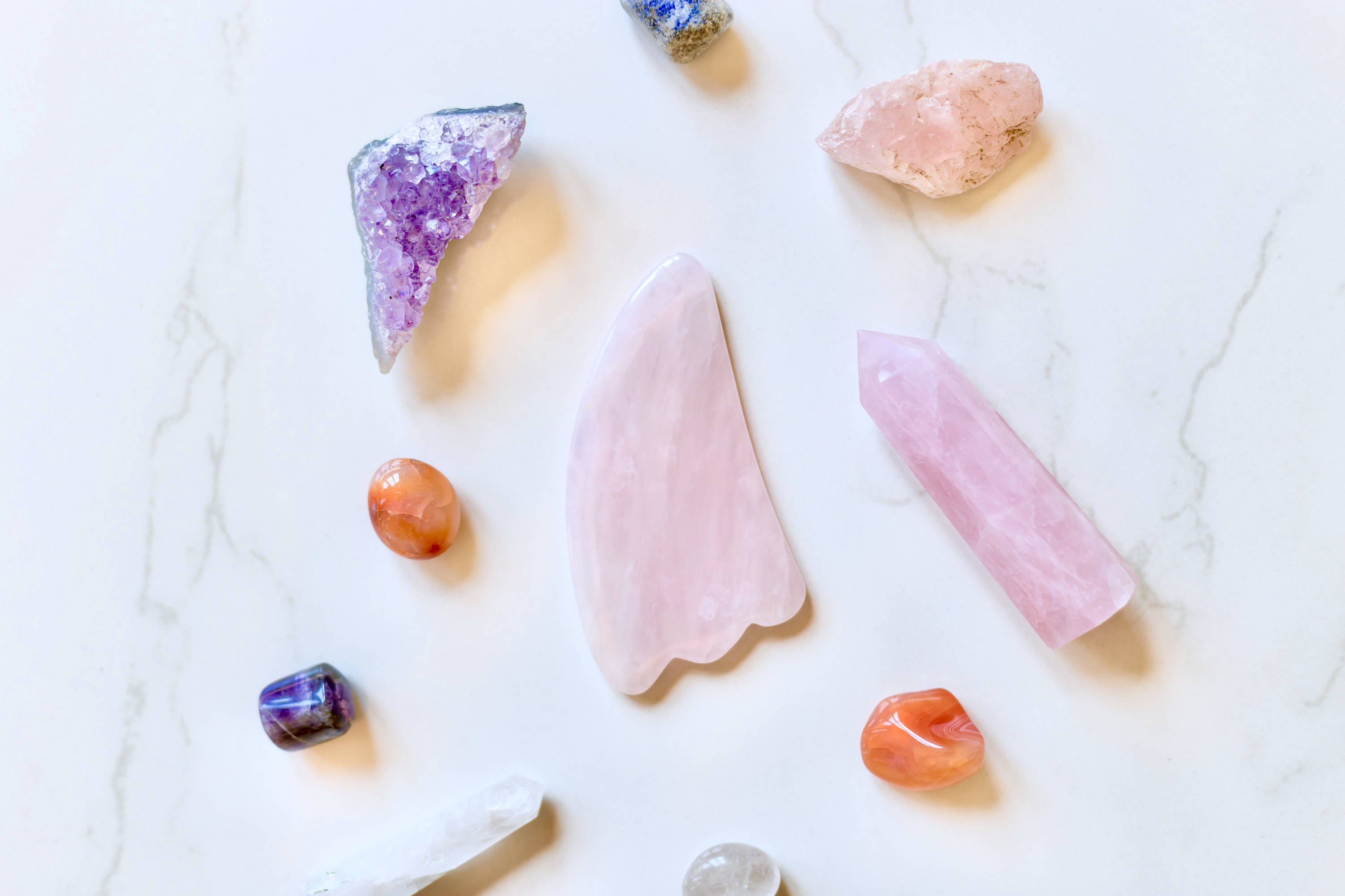 Rose Quartz Gua Sha surrounded by crystals