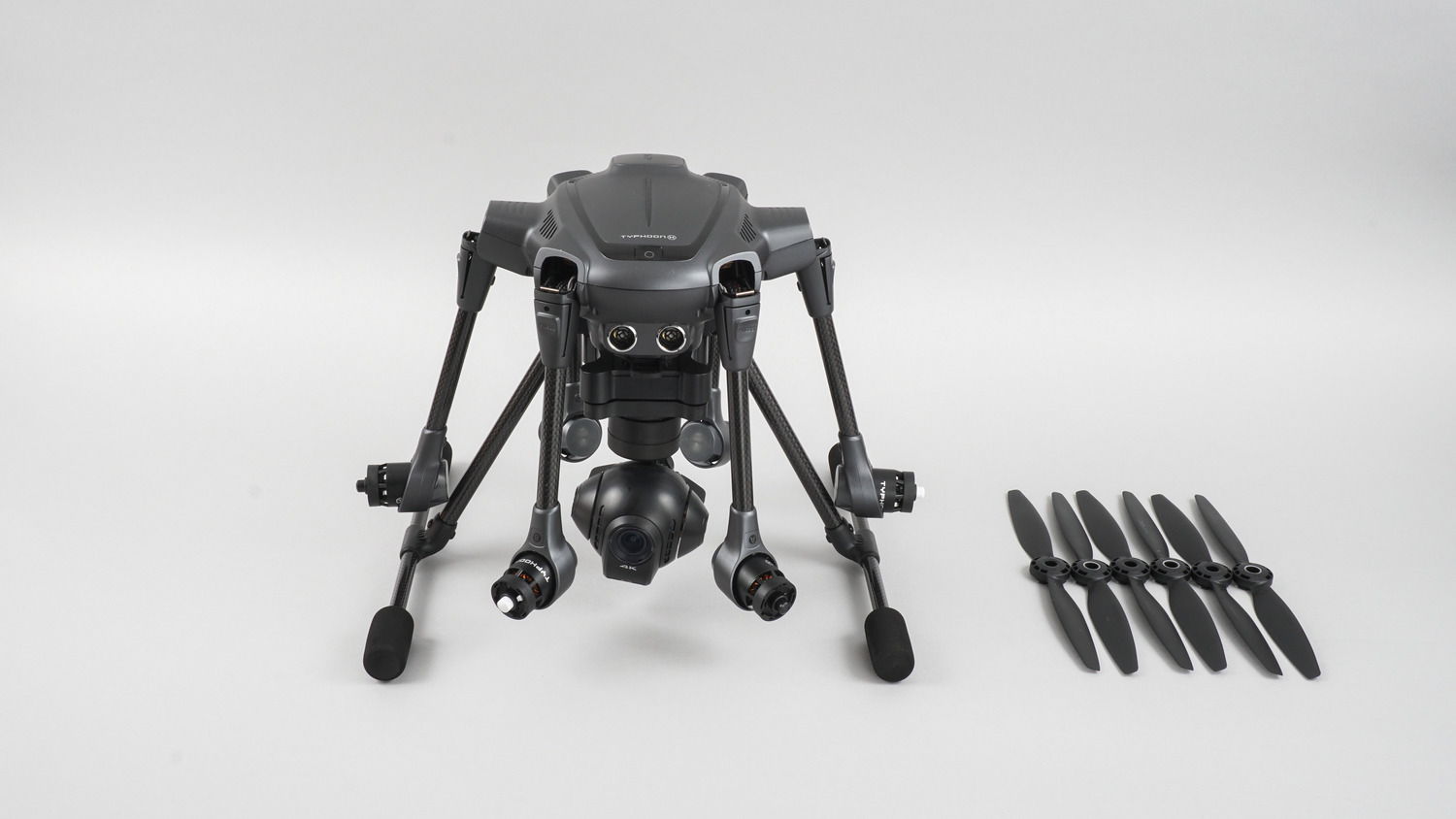 A folded Typhoon H resting beside spare propellers on a white background.