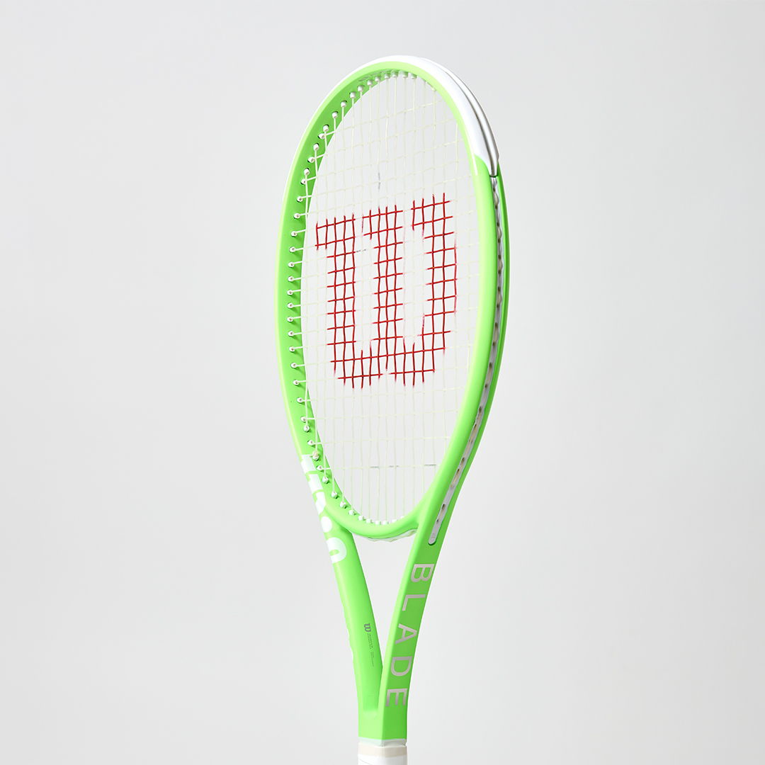 Green tennis racket with Wilson logo on a white background.