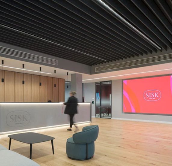 Modern office reception area with a large screen and wooden floor.