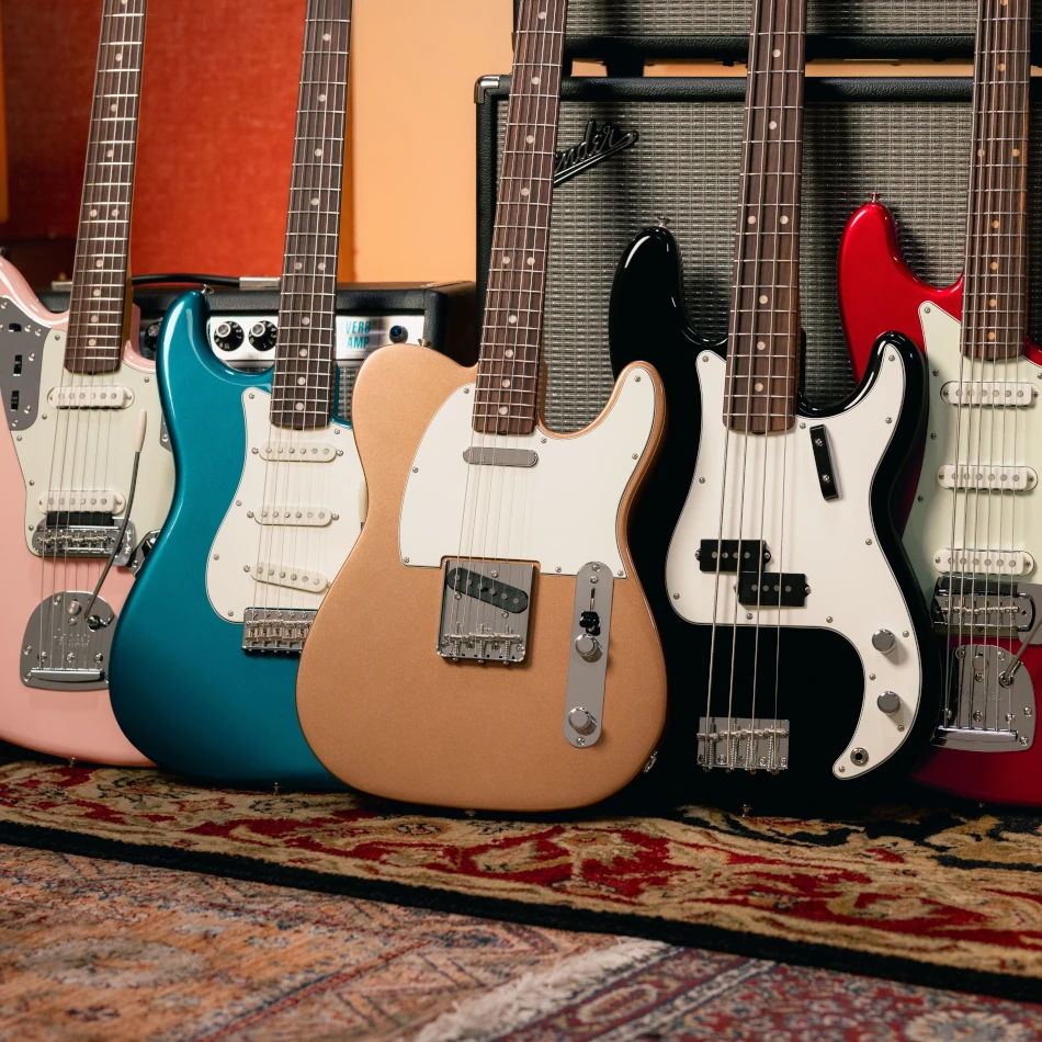 Various Fender Vintera III guitars and basses on a rug in front of an amp