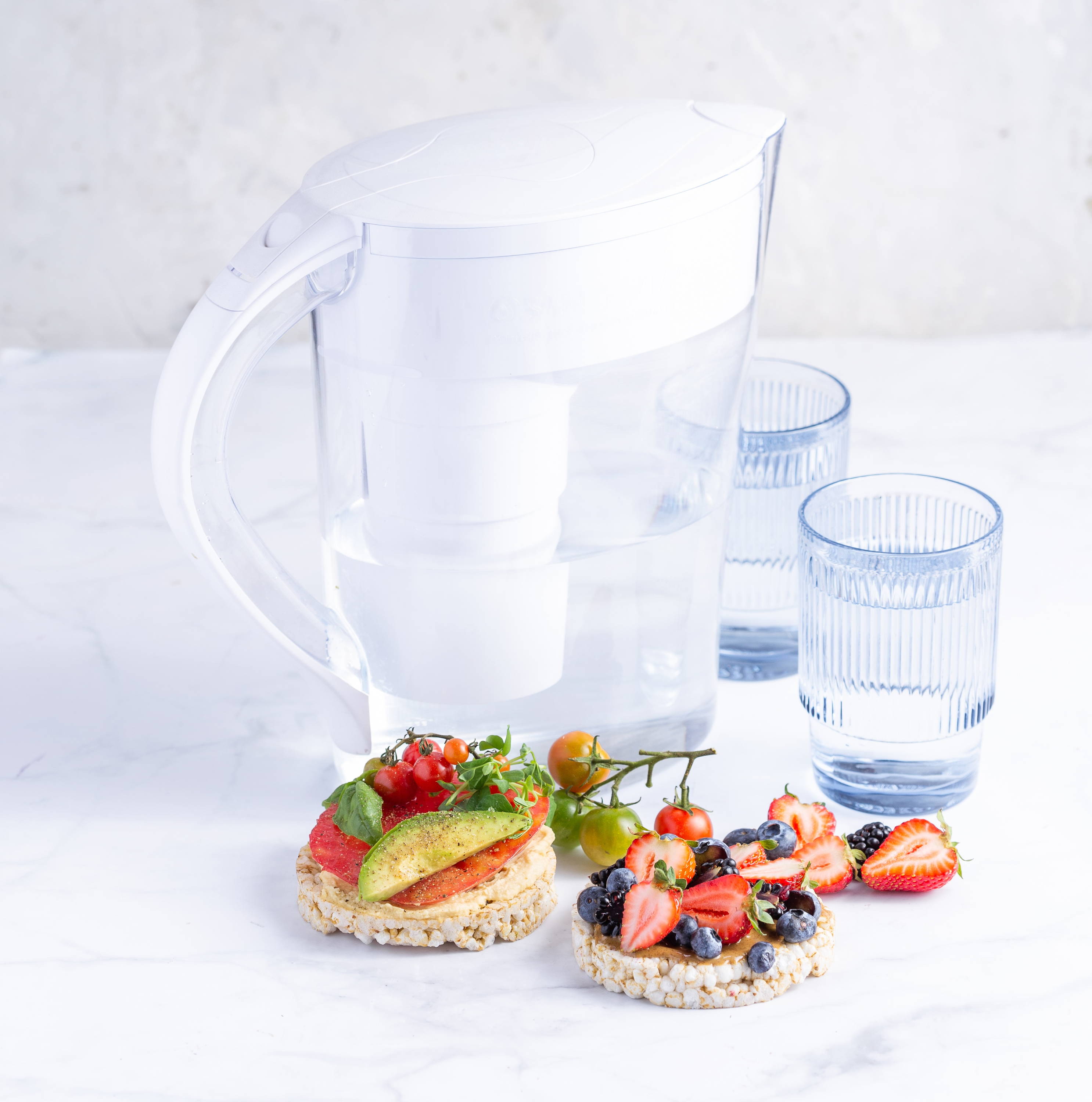 Water pitcher with glasses and food in front