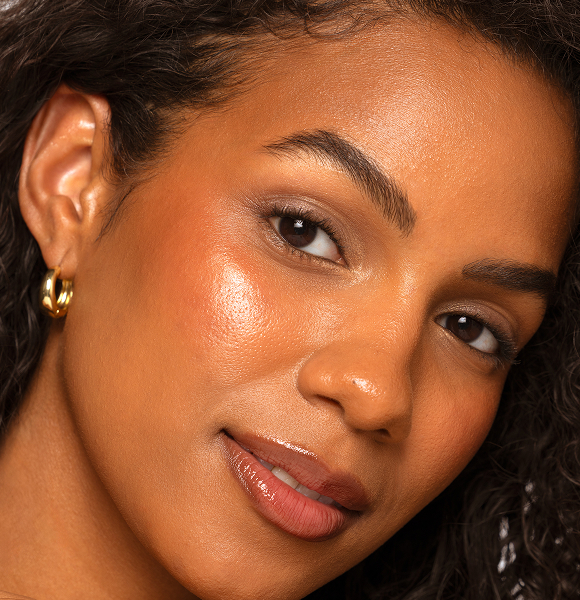 Close-up of a woman with curly hair and warm skin tone smiling.