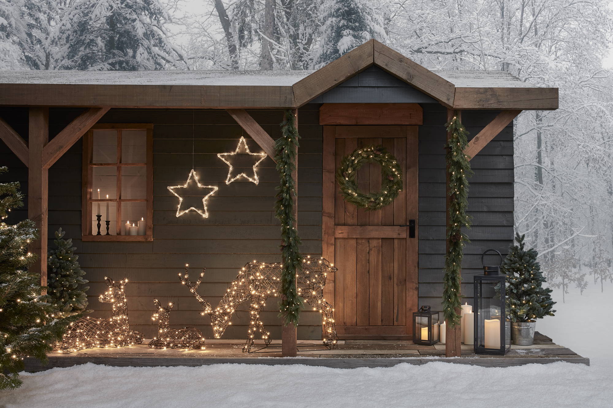 A winter wonderland setting with light up reindeer around a cottage.