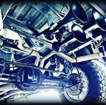 Low-angle view of four-trumpet train horn kit mounted above rear axle on vehicle undercarriage