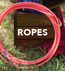 A circular rope on grass near a wooden box.