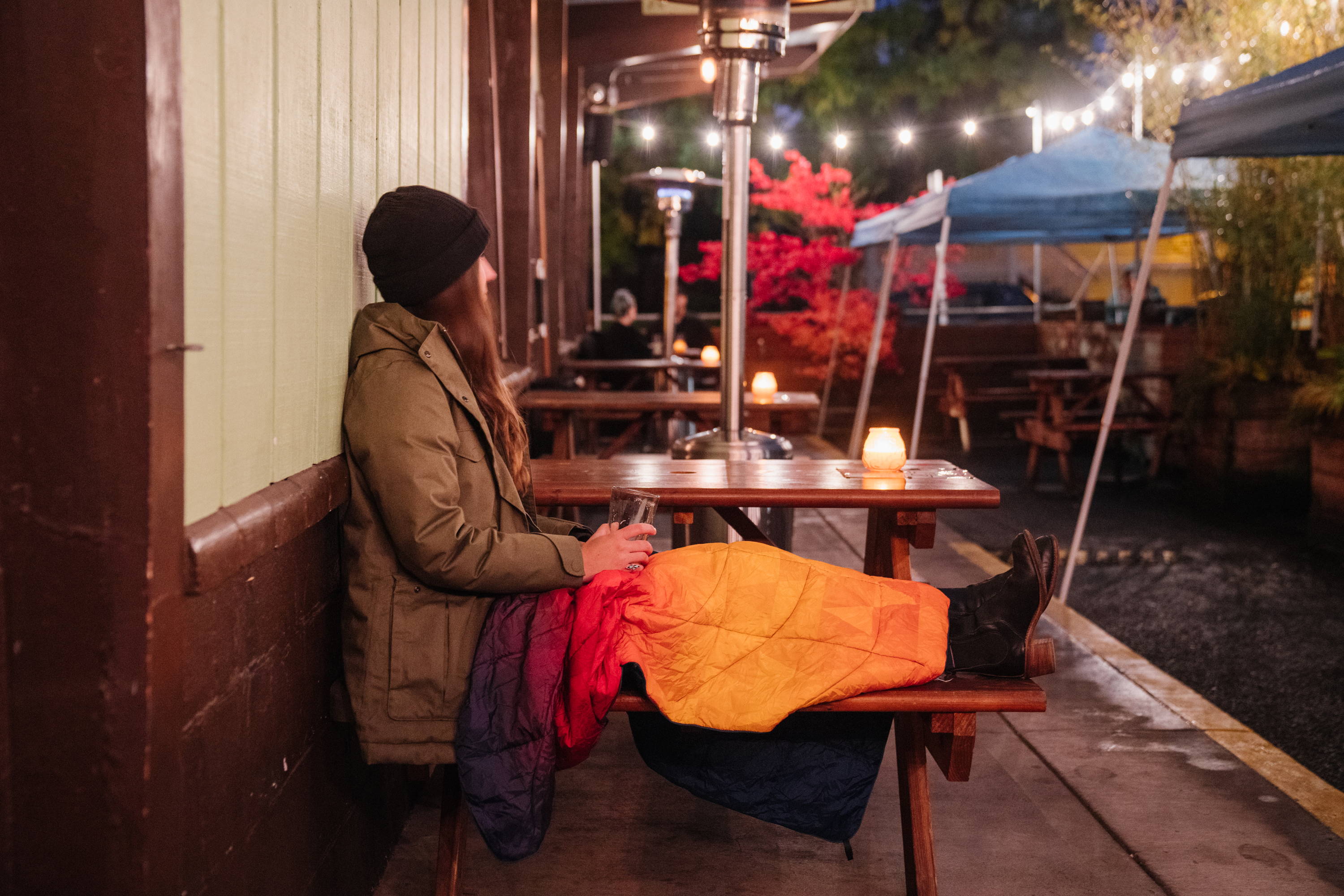 Woman wearing Rumpl travel blanket on lap outside