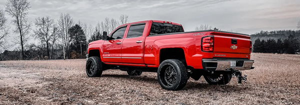 Rear three-quarter view of Justin's red 2017 Chevrolet 2500HD parked in a field, Shocker XL train horn install photo 1