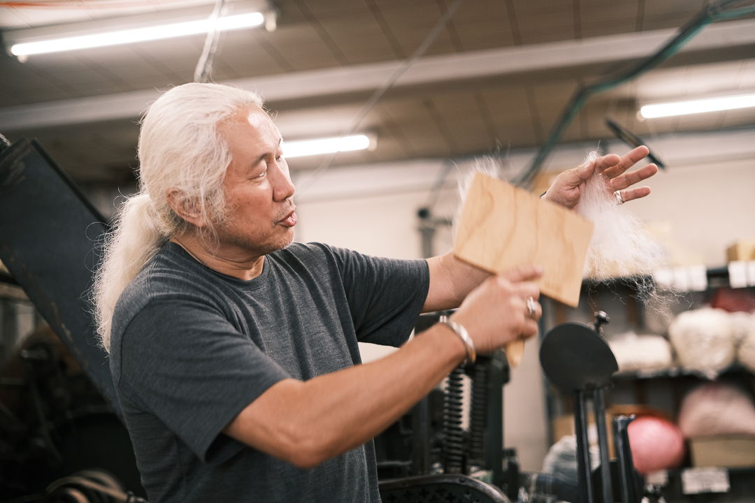 Person demonstrating craftsmanship in a workshop, holding a piece of material.