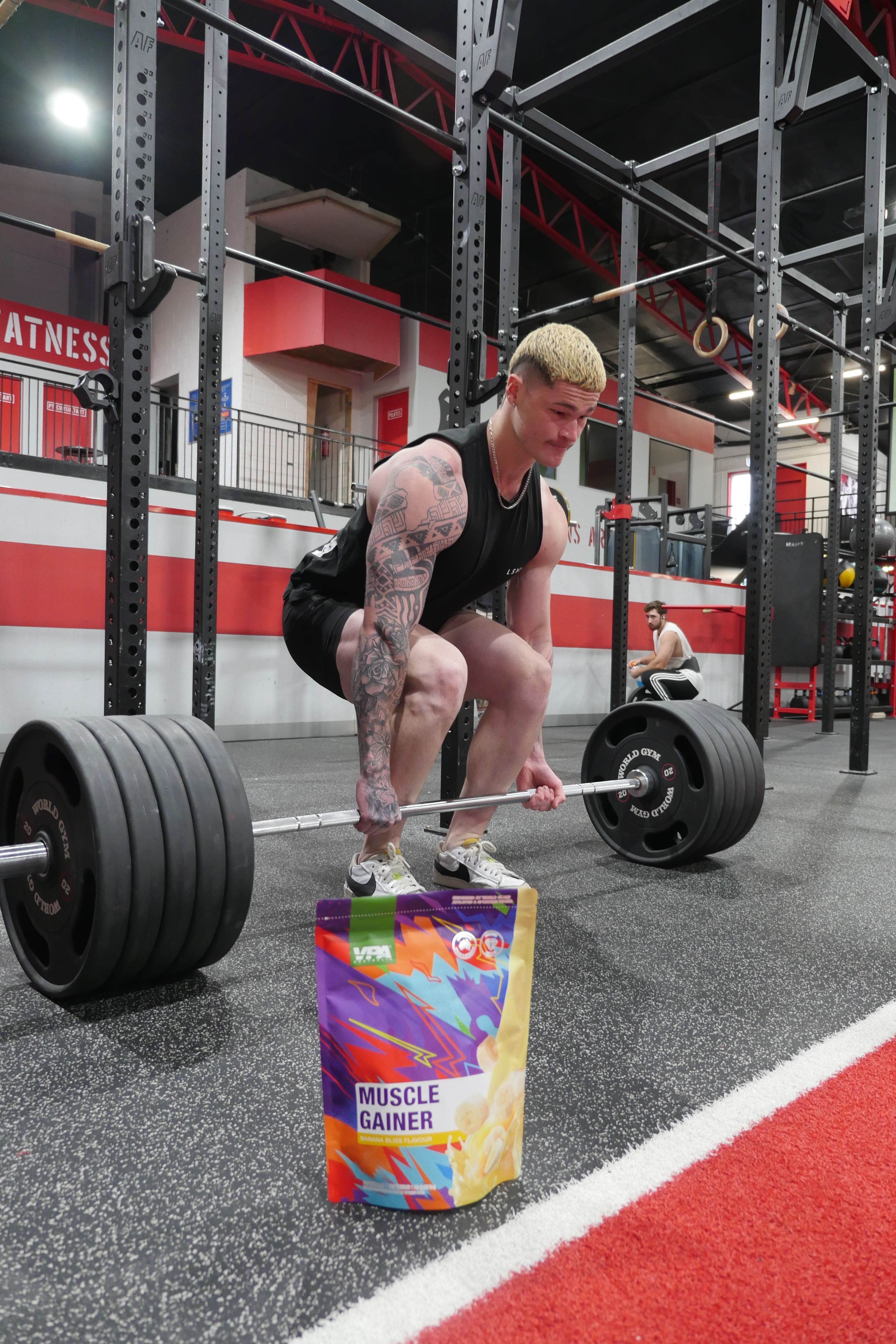 Person lifting a barbell with weights in a gym setting.