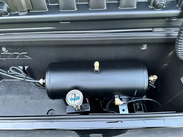 Close-up of black air tank with HornBlasters pressure gauge installed in storage box