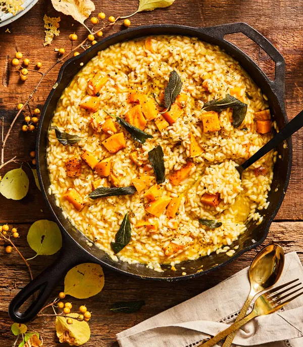 Risotto mixed with sage and butternut squash prepared in a cast iron skillet