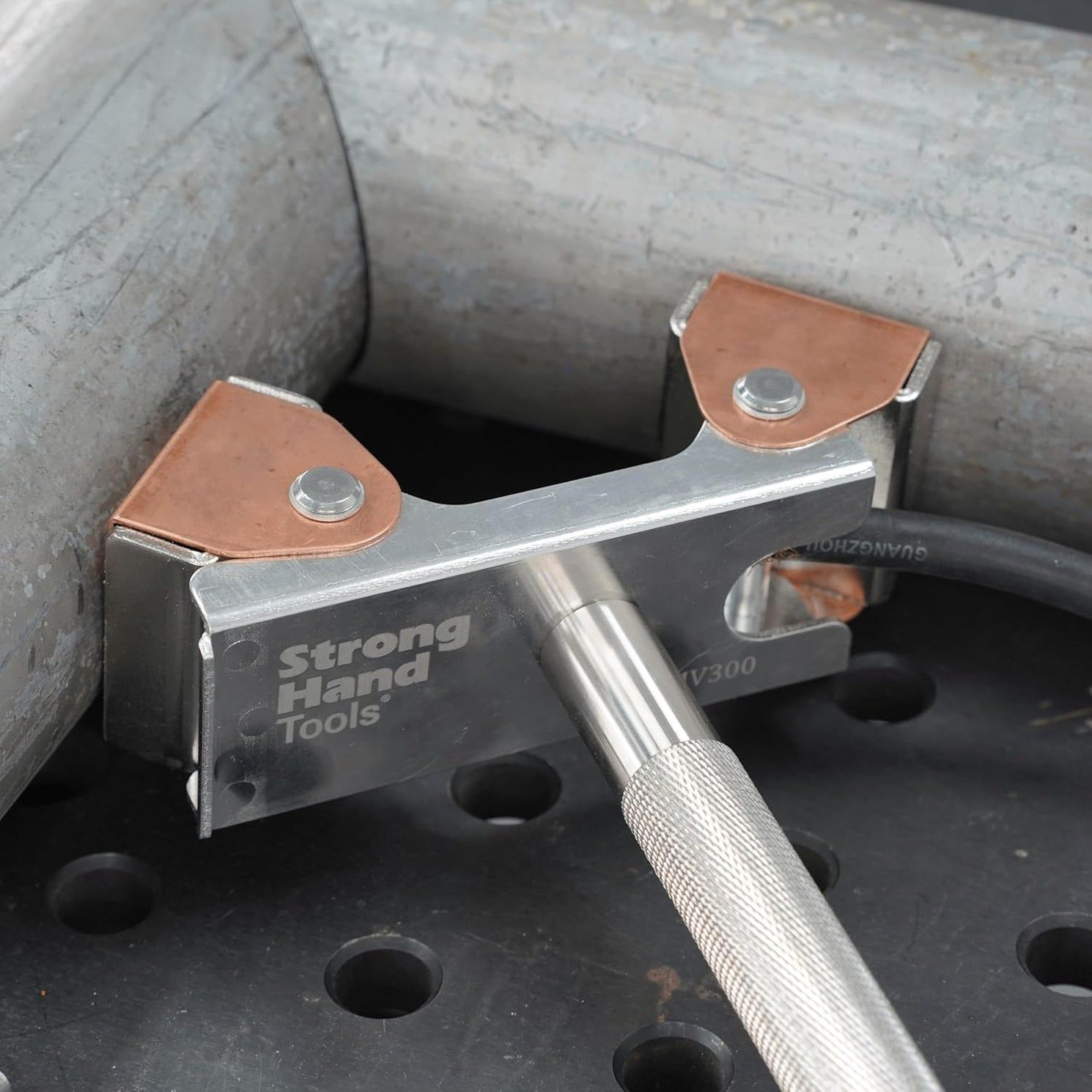 Metal clamp securing a pipe with a screwdriver nearby.