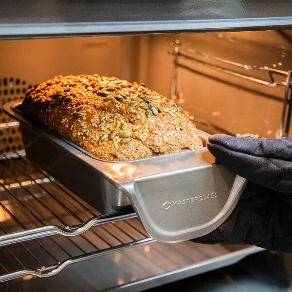 A loaf cake being taken out of an oven.