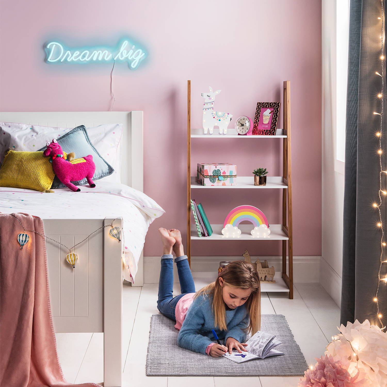 Girl's bedroom with dream big neon sign displayed on pink wall with rainbow and llama light on shelves