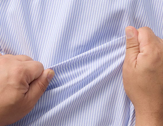 Person gripping and pulling a blue and white striped shirt.