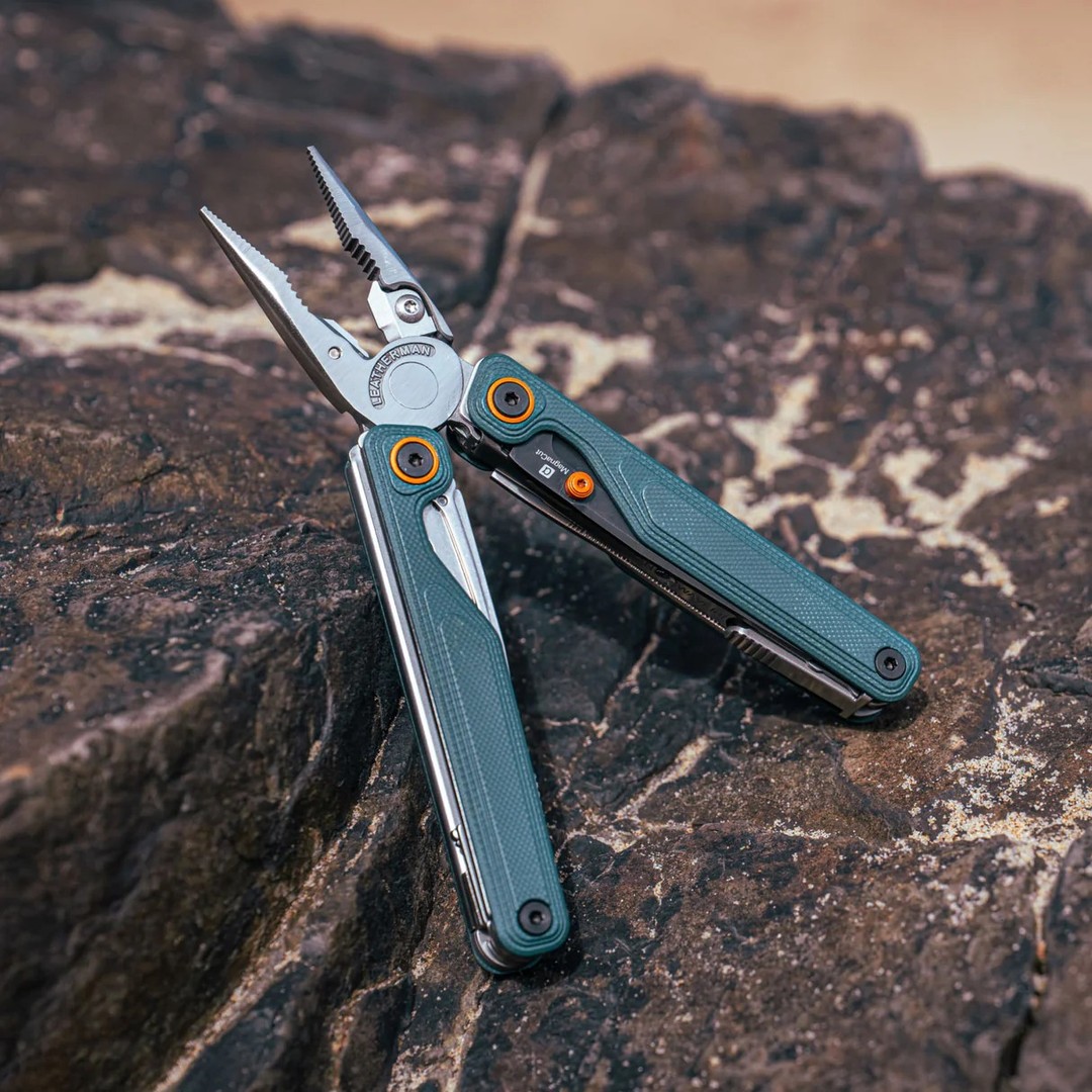Multitool with scissors resting on a textured rock surface.