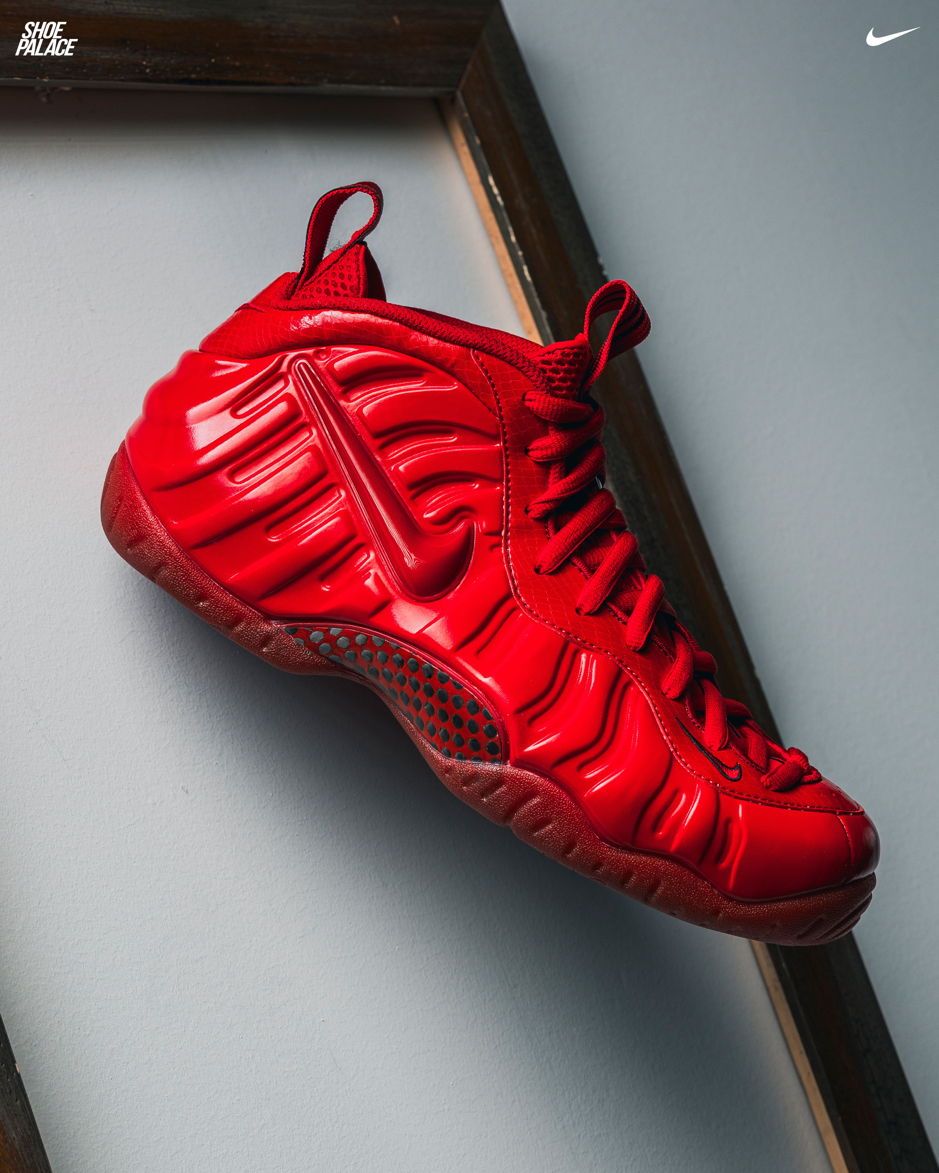 Red Nike Foamposite sneaker displayed on a light background.