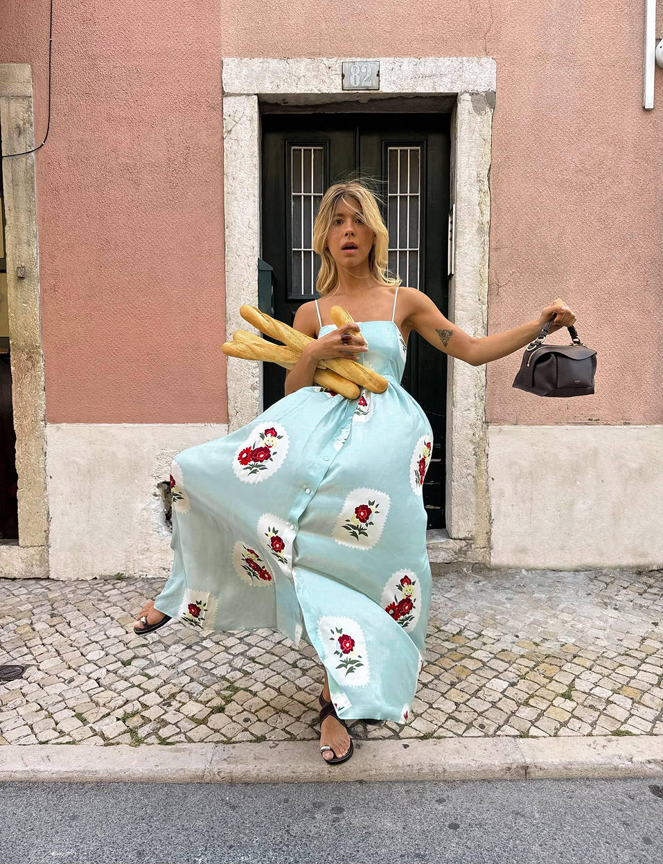 Model, Ines wearing a teal coloured maxi dress while juggling baguettes and a leather chocolate coloured bag.