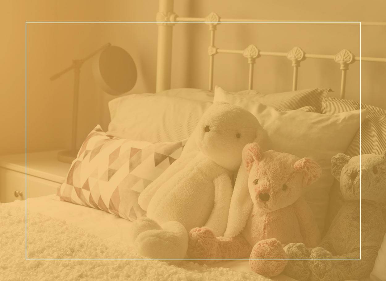 Pink, white and grey teddy bears on a pristine white bed. Dust mites thrive in bedrooms and can make you sick.