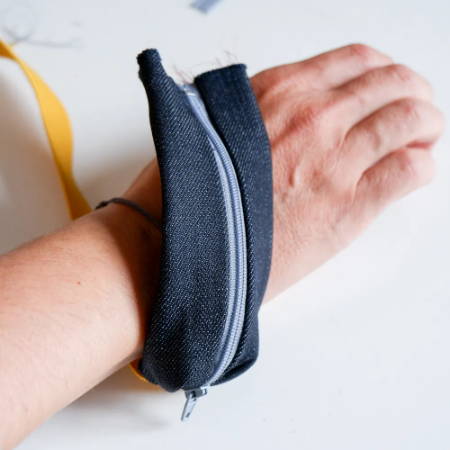Testing a half finished wrist pouch around a wrist to see if the elastic fits