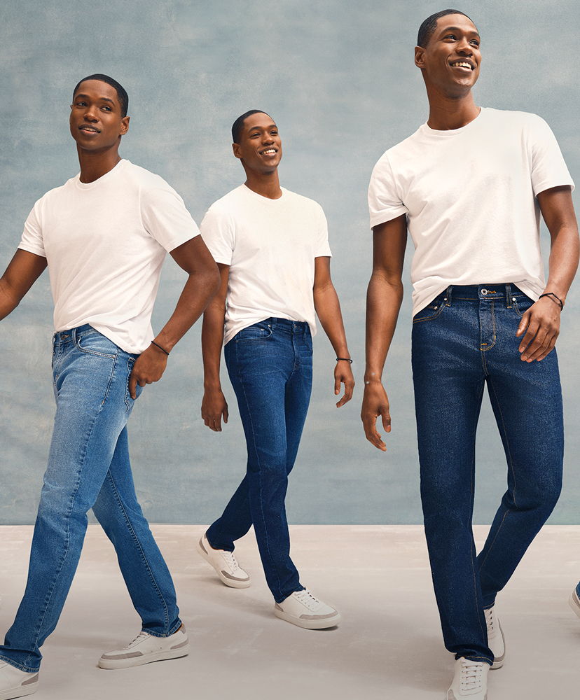 Three men in white t-shirts and jeans walking against a blue background.