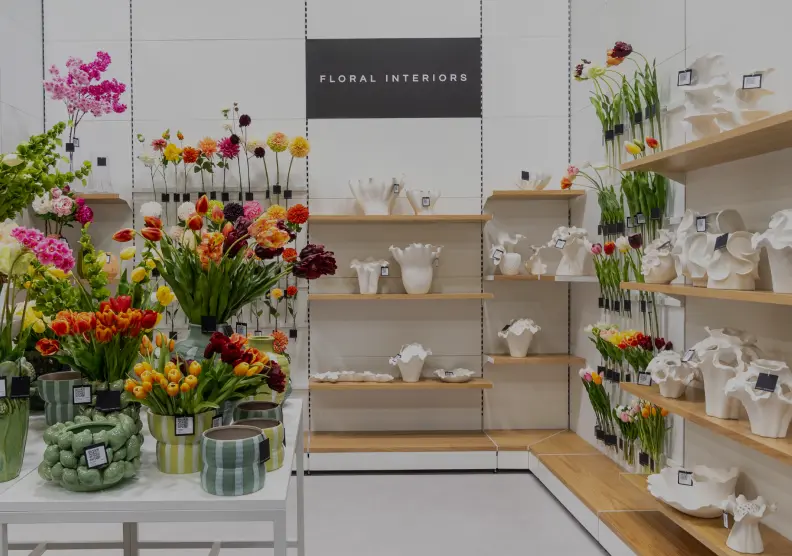 Colorful flower arrangements and white ceramic vases displayed in a shop.