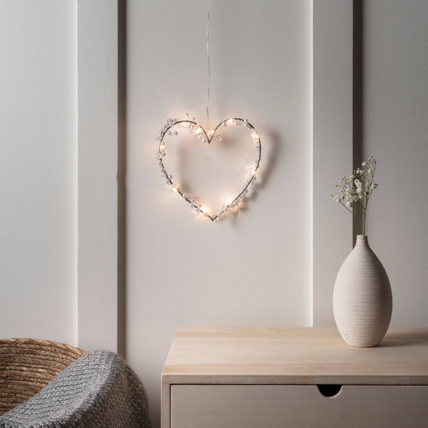 Beaded heart light hanging above a side table in a bedroom.