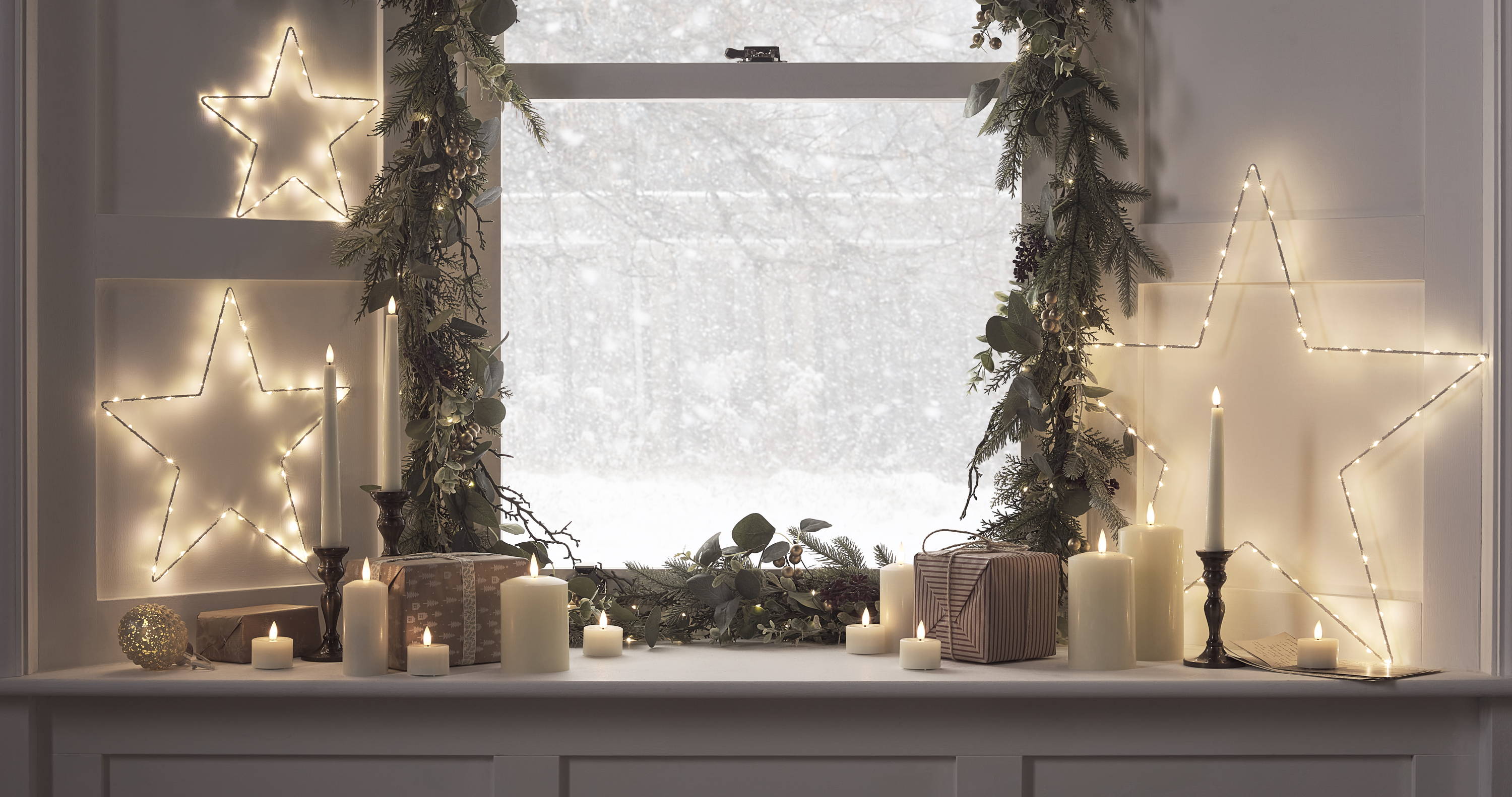 Ein mit LED Sternen, LED Kerzen und Weihnachtsgirlanden  dekorierertes Fenster
