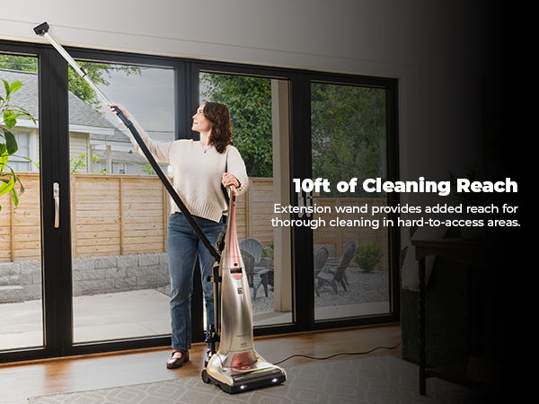 Person using a vacuum cleaner with a long reach in a bright room.