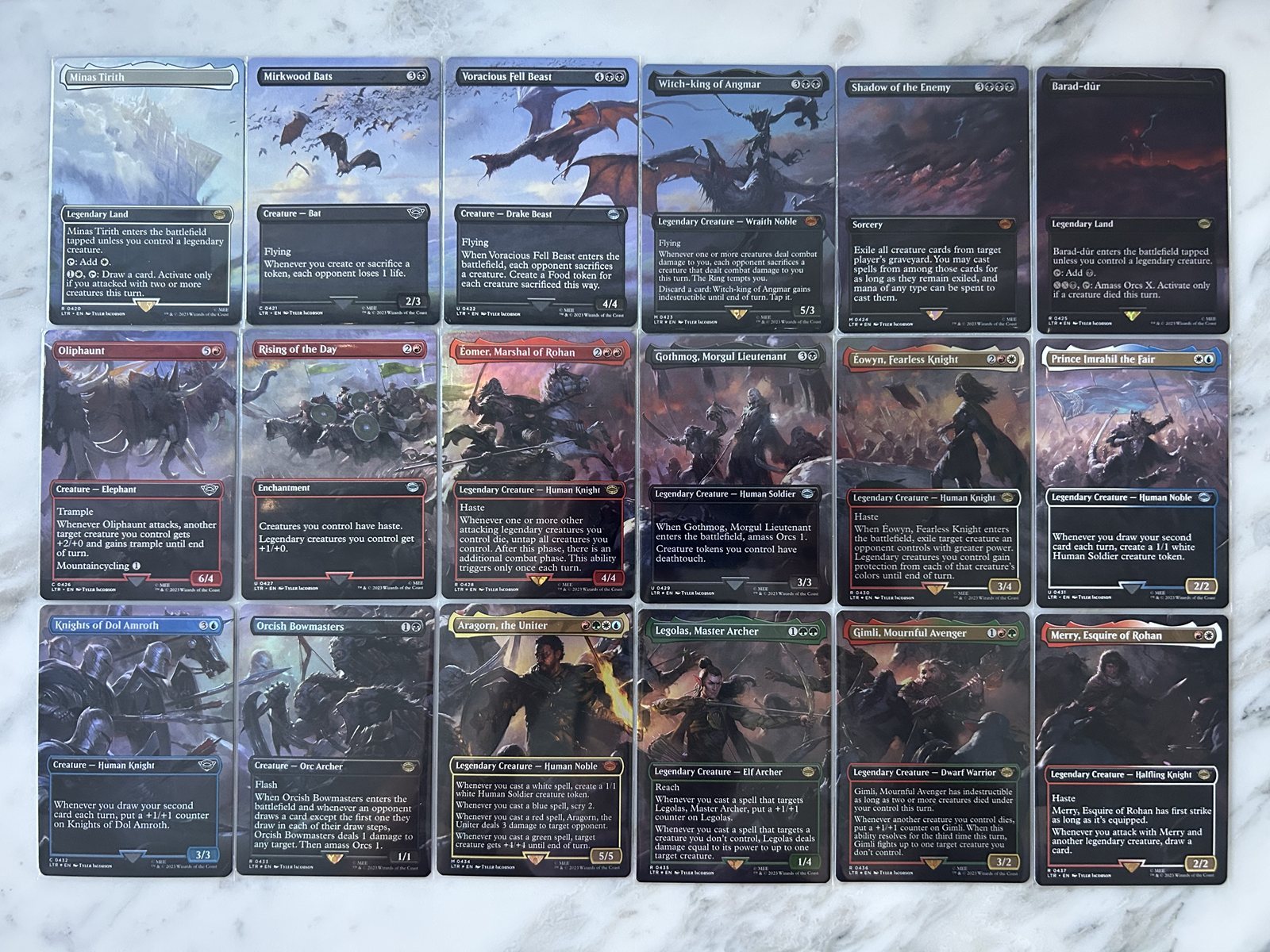 A collection of lord of the rings mtg cards arranged in rows on a surface.