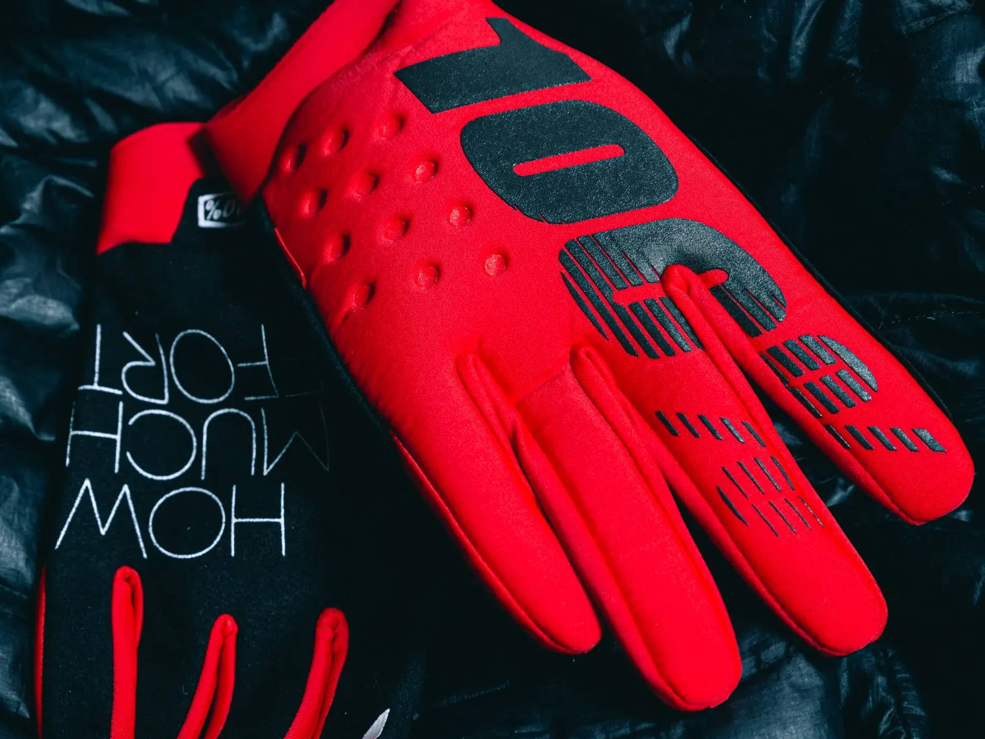 red 100% brisker mtb gloves on a black jacket showing detail of top of glove and the palm of the glove