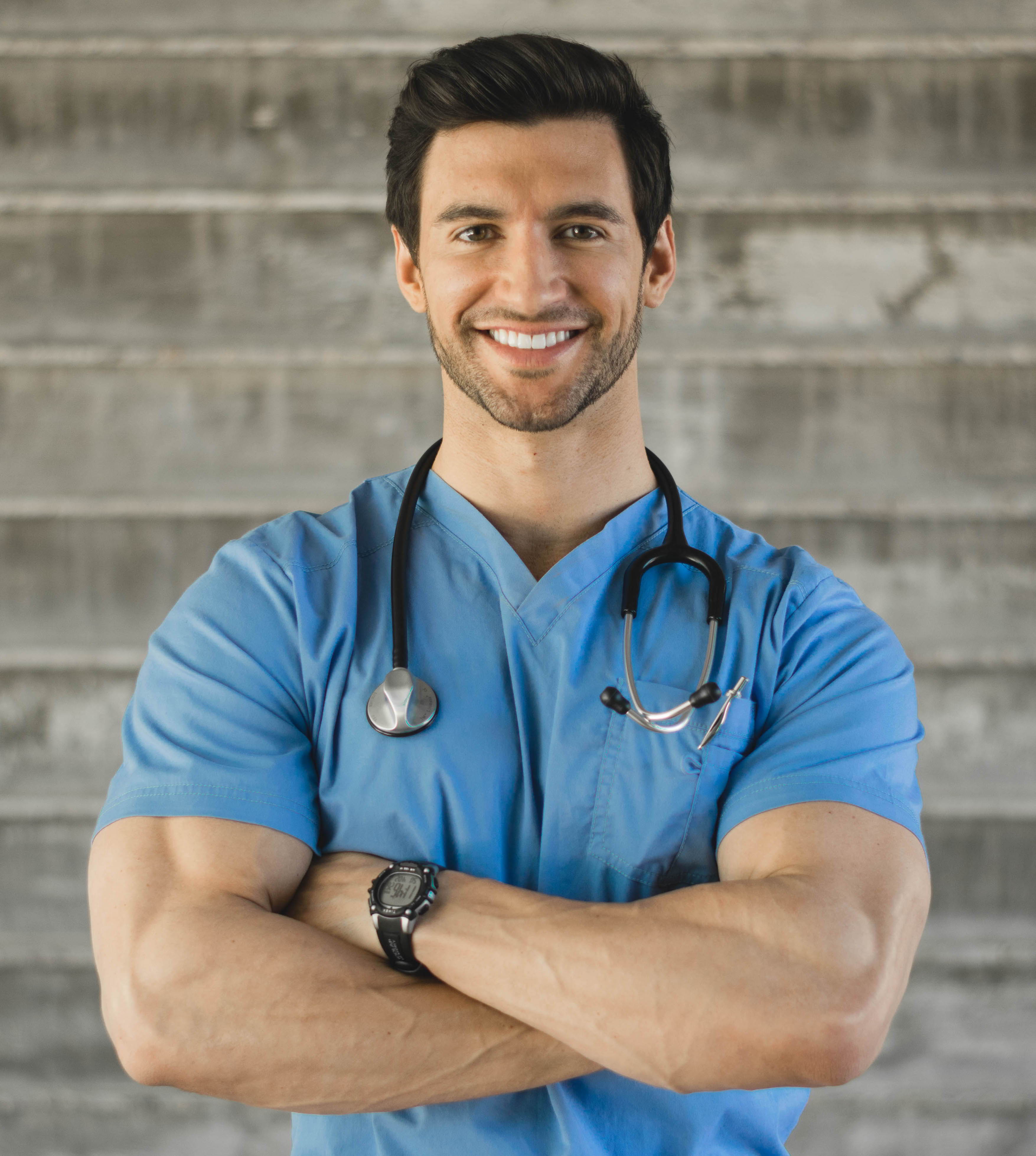 Smiling male healthcare professional in blue scrubs with stethoscope.