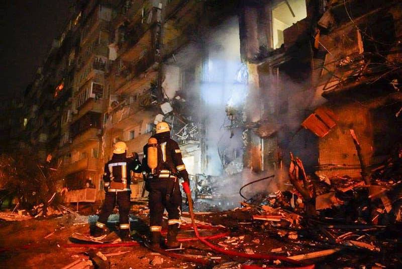 Ukrainian firefighters looking at bombed building