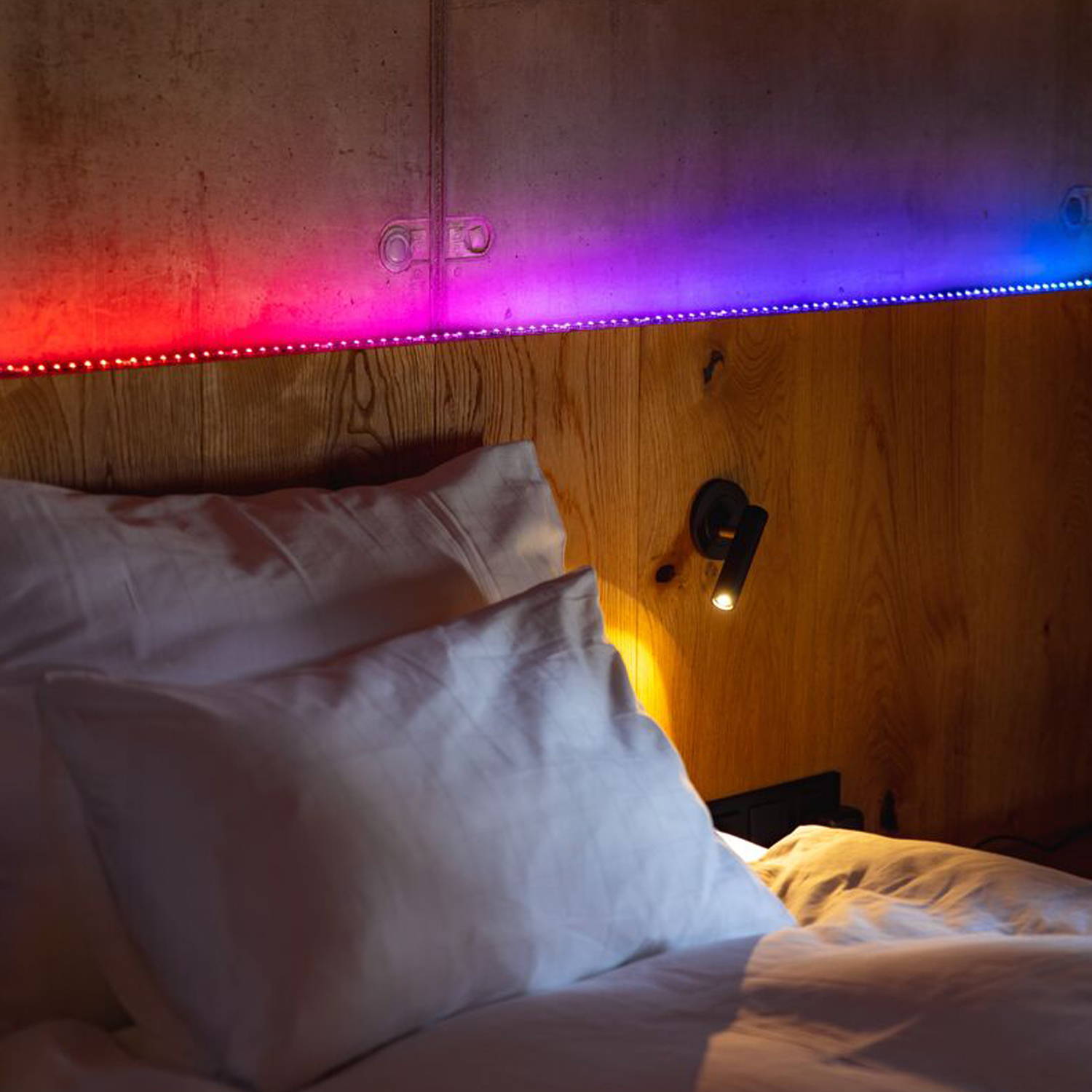 A multi coloured Twinkly Line abouve a headboard.