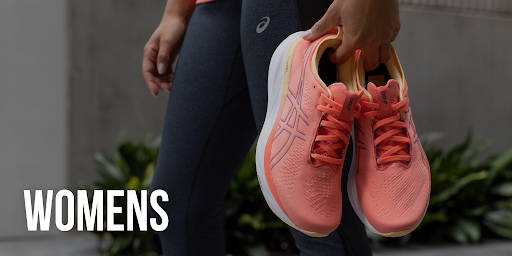 Woman holding pink Asics running shoes