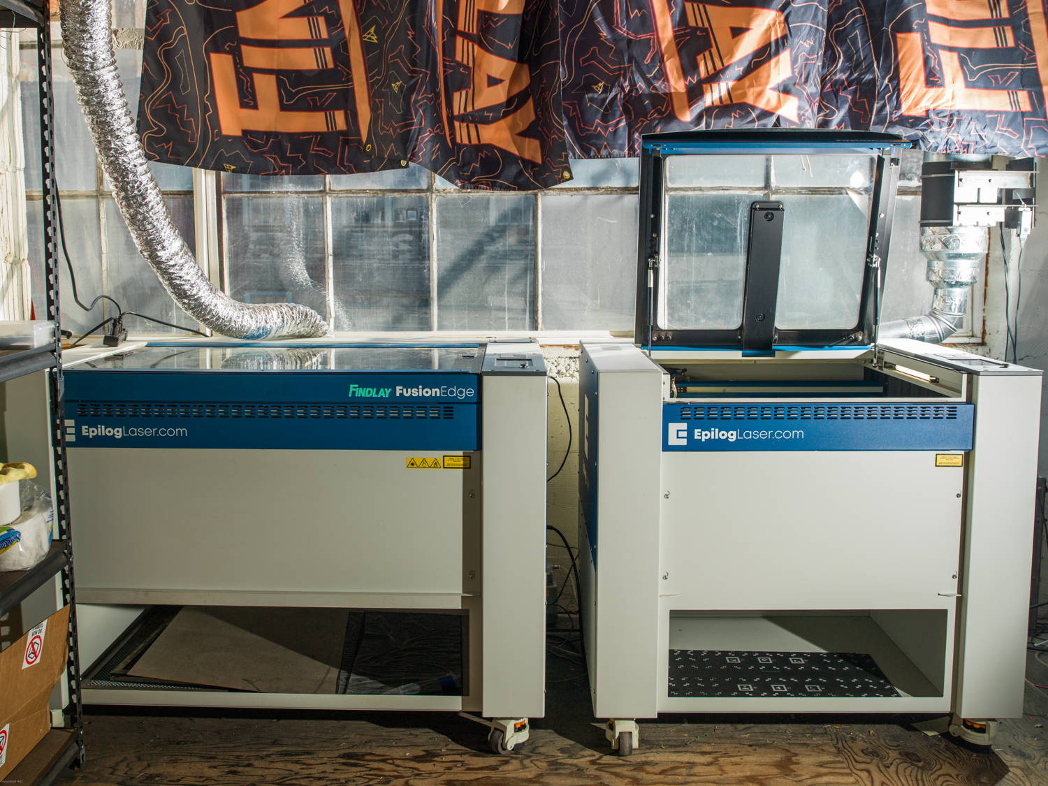 Two Epilog laser cutting machines under a Findlay banner.
