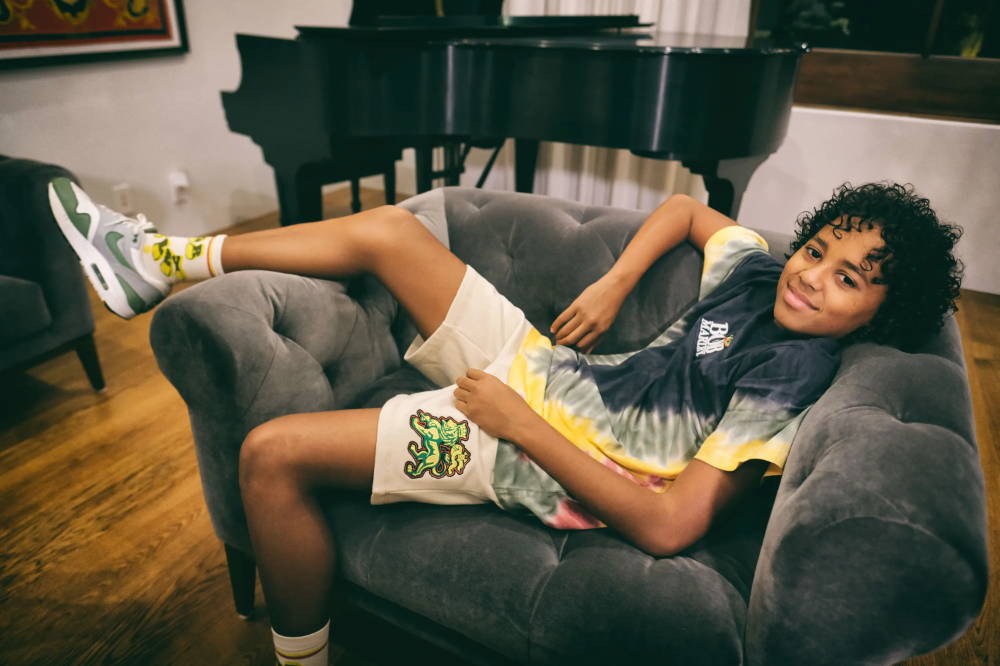 gideon marley in shoe palace x bob marley apparel laying on couch