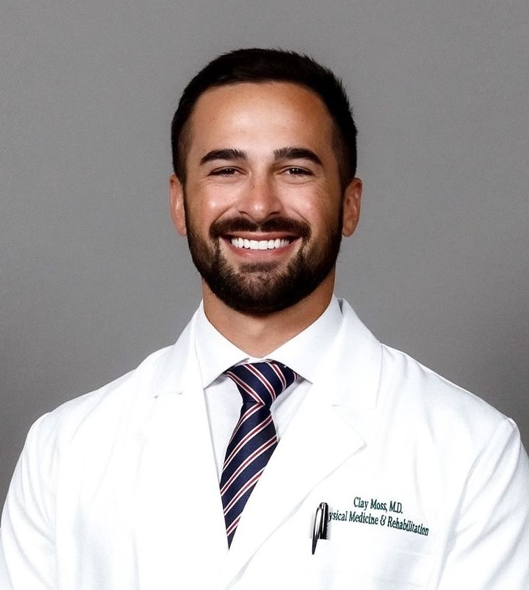 Smiling man in a white coat with a tie, posing for a professional photo.