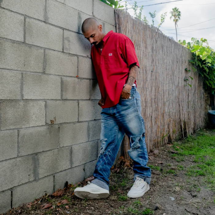 man leaning against wall wearing reebok shoes
