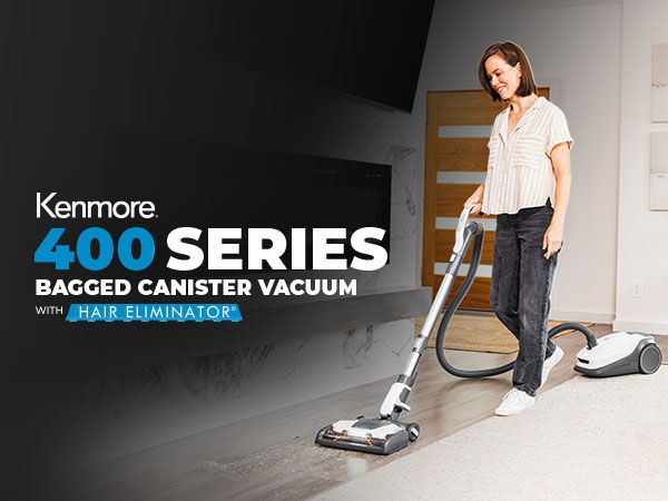 Woman using Kenmore 400 Series bagged canister vacuum in a modern room.