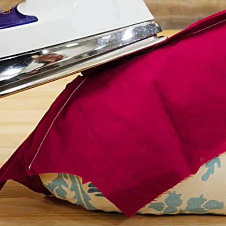 Pressing a curved seam on a tailor’s ham with an iron