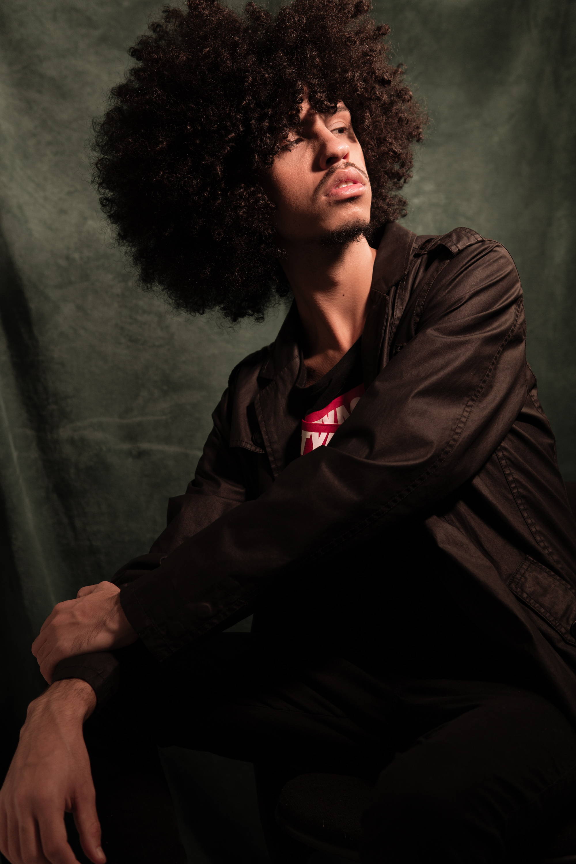 afro haired guy wearing leather jacket facing to the right for model pose