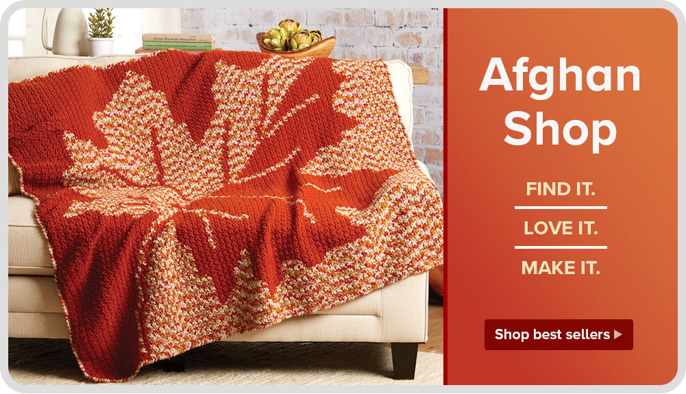 A cozy blanket with a maple leaf design on a couch.
