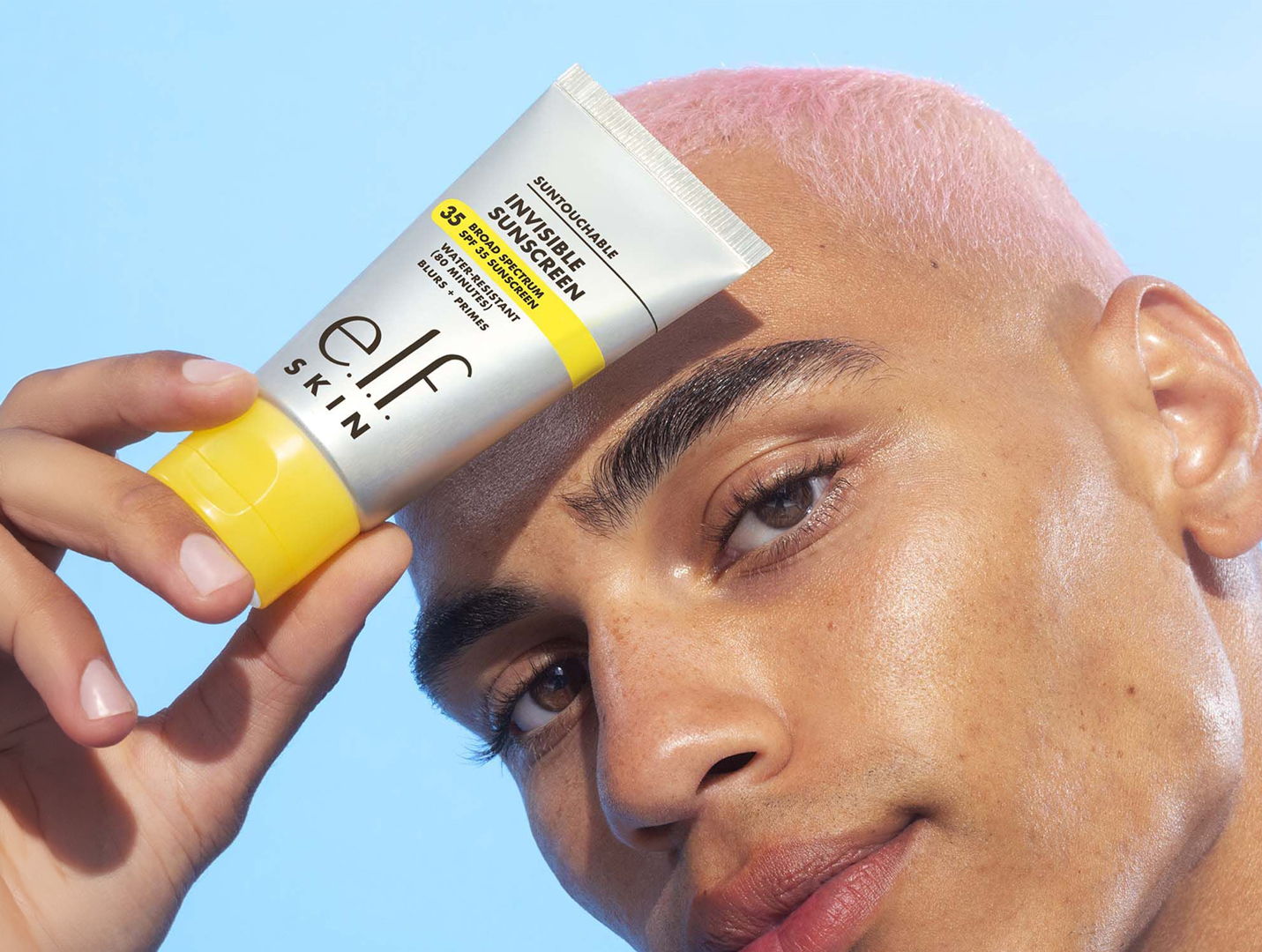 Person holding a tube of skincare product against a blue background.
