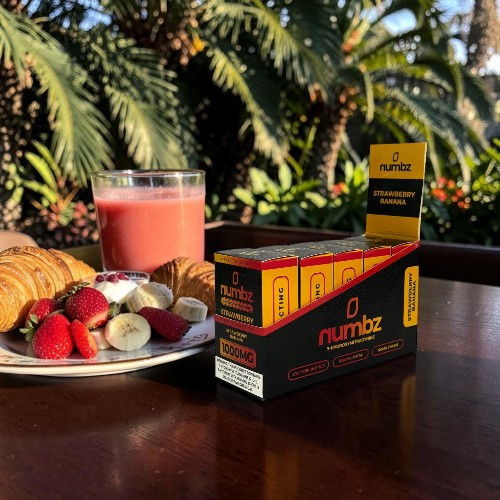 A box of Numba, fruit, cookies, and a drink on a table outdoors.