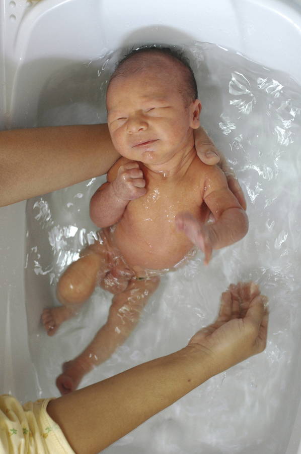 Un recién nacido en la bañera recibe cuidados pensados para su piel gracias a la cesta de regalo para bebé de Mustela