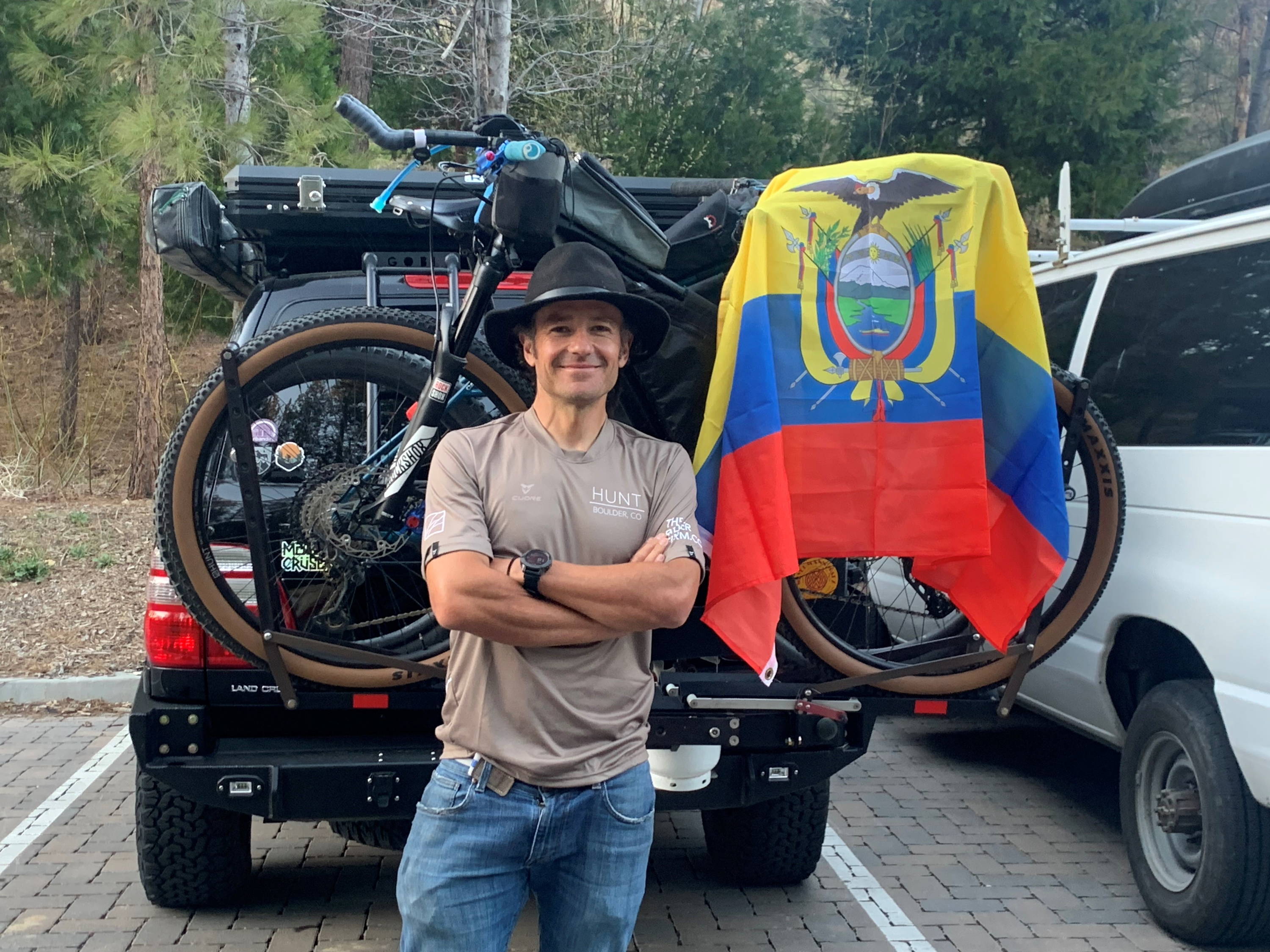 Xavier smiling in front of his bike and Ecuadorian flag