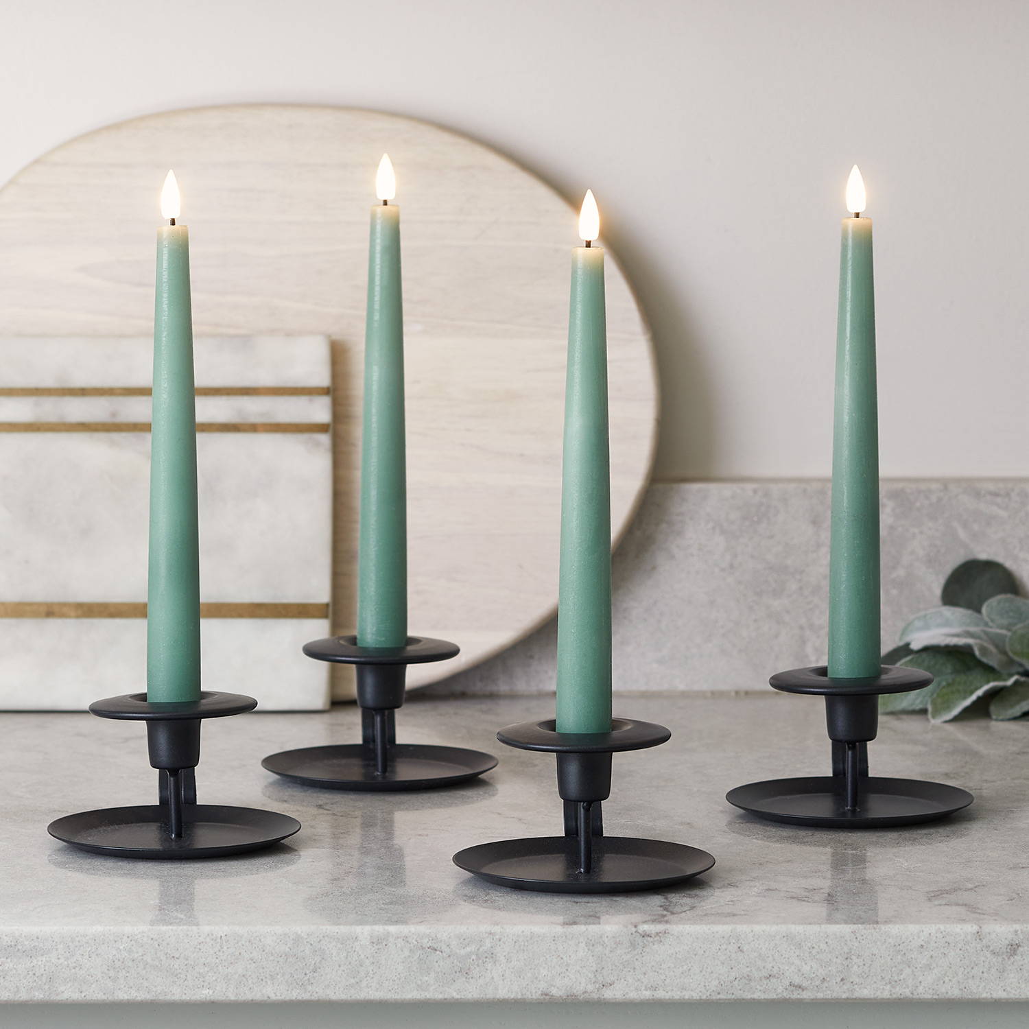 Green LED taper candles on a kitchen surface in black candle holders